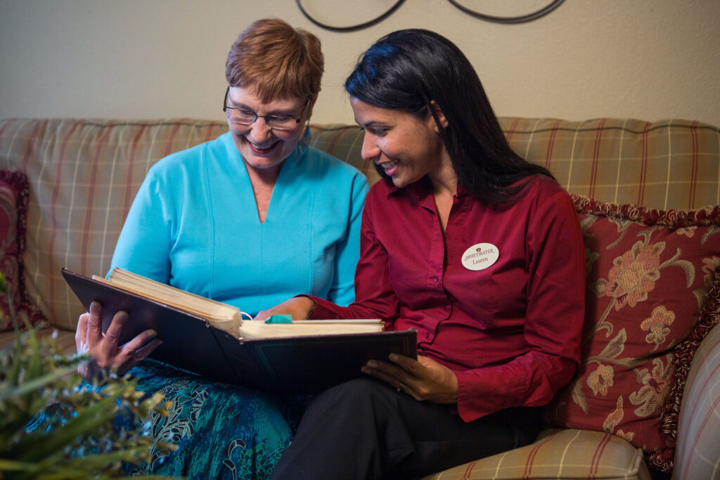 Senior woman and Sweetwater care giver looking at a photo album