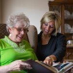 Older woman and middle aged woman looking at a photo album together