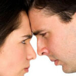 Man and woman touching foreheads frowning at each other
