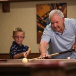 Older man and younger boy playing pool together