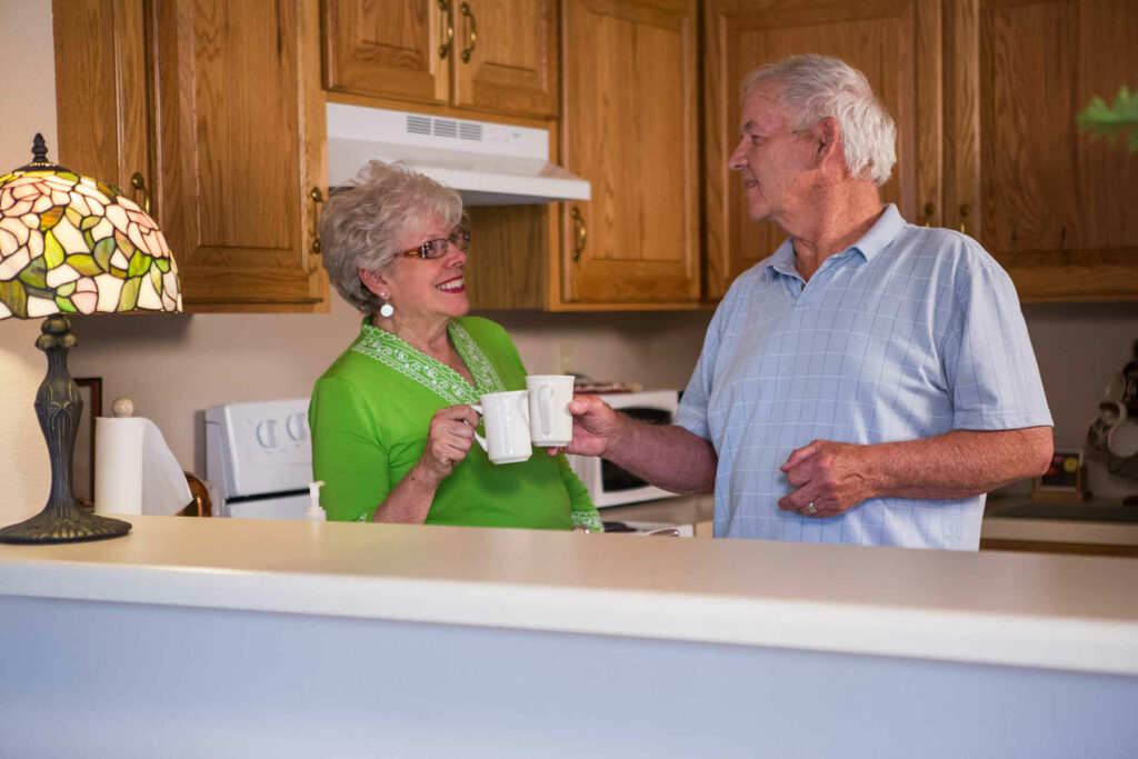 Older couple touching mugs smiling at each other