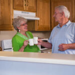 Older couple touching mugs smiling at each other
