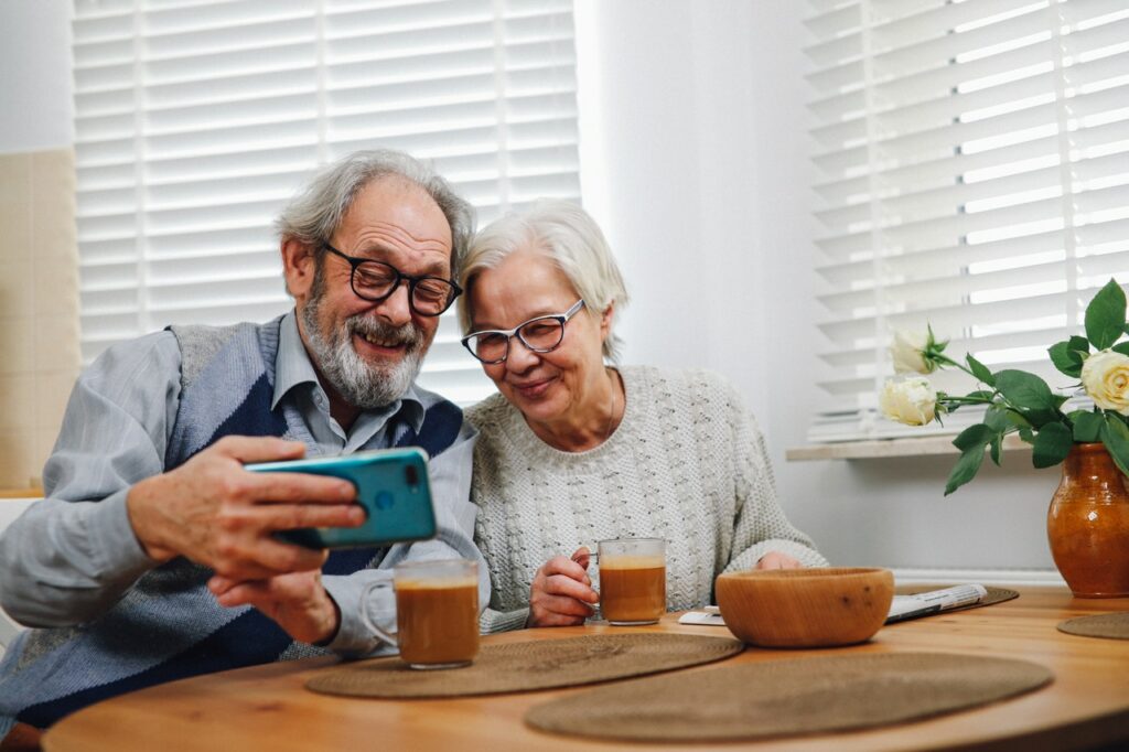 Older couple looking at smartphone at kitchen table.