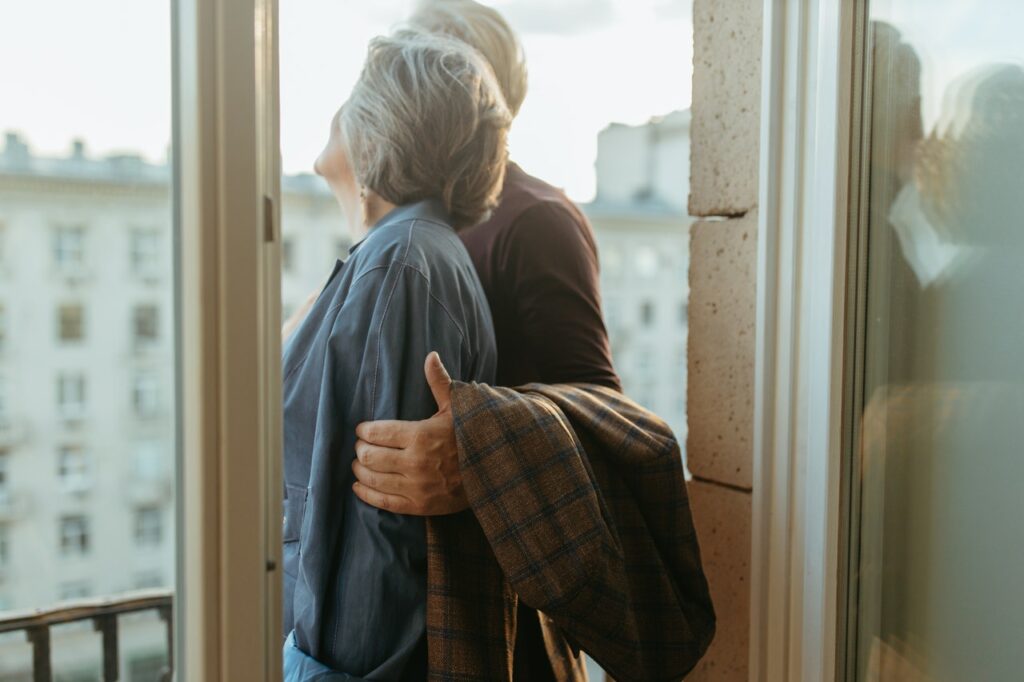 Older couple on a balcony looking outside