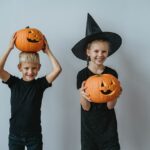 Two young kids holding jack o lanterns