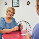 Sweetwater staff member playing a game of cards with resident to help fight loneliness.