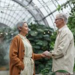 Elderly couple holding hands in indoor garden area.