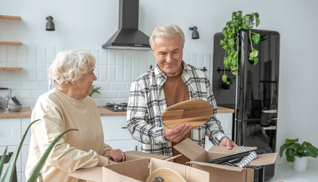 senior couple packing boxes in the kitchen to move
