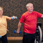 Senior couple using hand weights to exercise in the fitness room